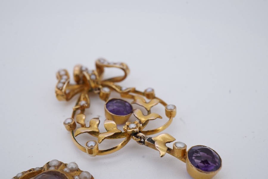 An amethyst and seed pearl demi-parure, early 20th century, comprising: a pendant of foliate design surmounted by a bow, set with oval amethysts and seed pearls, mounted in gold, length 5.2cm, and a matched pair of ameth